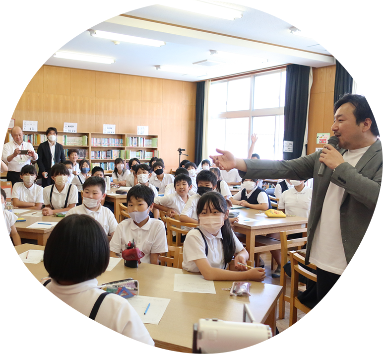教室でマイクを持って子どもたちに話しかけるホンミライ理事長の今村翔吾